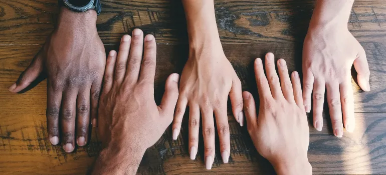 clay-banks-LjqARJaJotc-unsplash1.jpg Six diverse hands placed side by side on a wooden surface